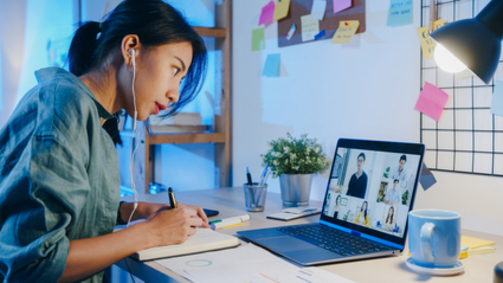 Asia businesswoman using laptop talk to colleagues about plan in video call meeting at living room. Working from house overload at night, remotely work, social distancing, quarantine for coronavirus.